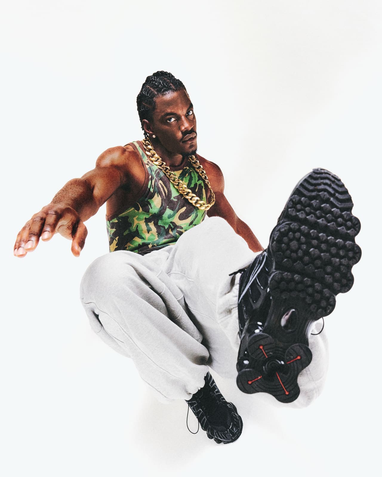Ibo in a camo tank top, sneaker sole toward the camera